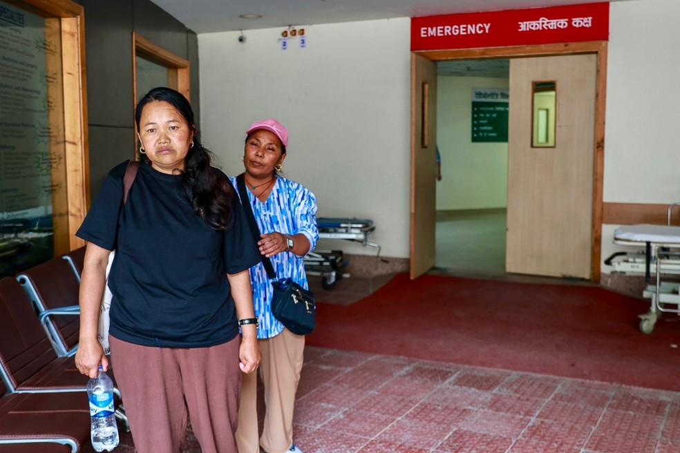 Damu Sherpa (à esquerda), esposa do alpinista Dawa Sherpa, é consolada por um parente no Hospital HAMS em Katmandu, em 4 de junho de 2026. — Foto: AFP
