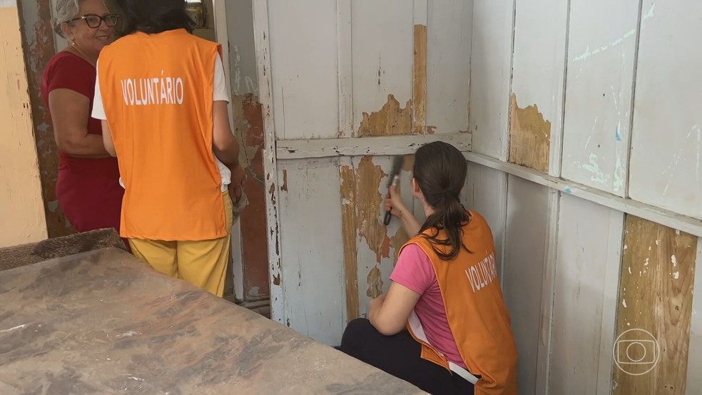Voluntários pintam casas de Porto Alegre que ficaram debaixo d'água na enchente histórica do RS — Foto: Reprodução/TV Globo