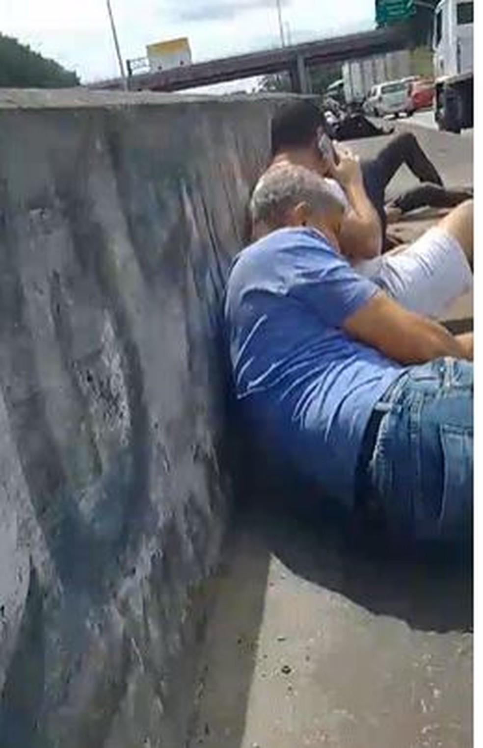 Pessoas se abrigam em uma mureta durante confronto — Foto: Reprodução
