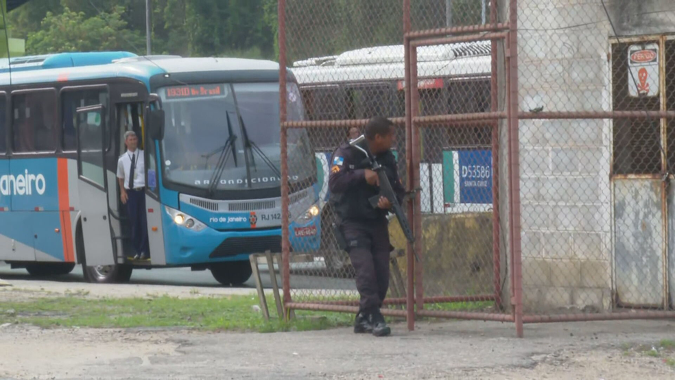 Policial militar se esconde em uma pilastra da Avenida Brasil na altura da Cidade Alta — Foto: Charles Mathura/TV Globo