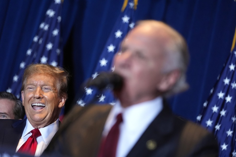 Trump (ao fundo) sorri durante festa de comemoração do resultado das primárias da Carolina do Sul neste sábado (24). — Foto: Andrew Harnik/AP