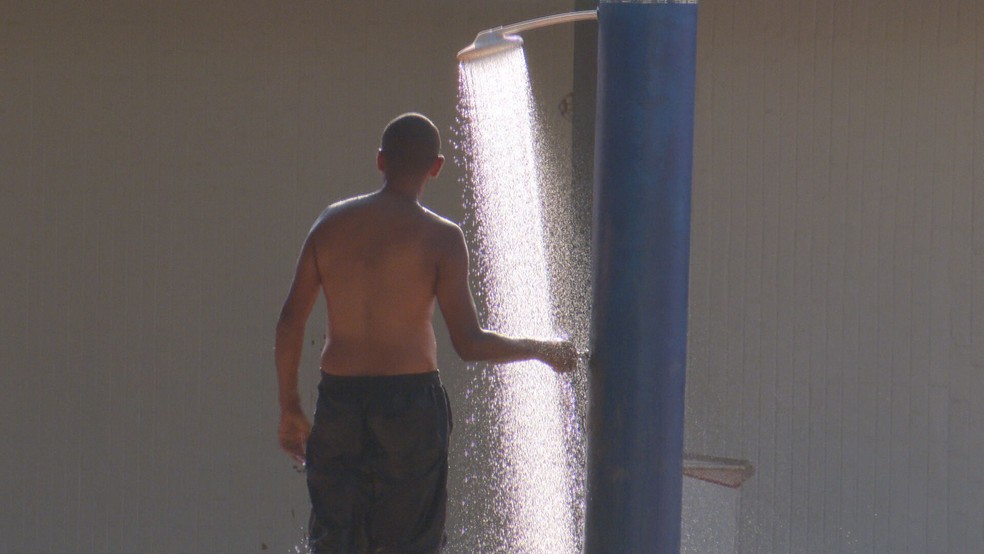 Moradores de Brasília usa chuveiro para amenizar calor da capital — Foto: TV Globo/Brasília