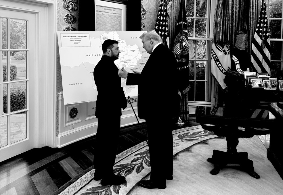 Presidentes dos Estados Unidos, Donald Trump, e da Ucrânia, Volodymyr Zelensky, conversam diante de um mapa da Ucrânia com regiões ocupadas pela Rússia marcadas por cor diferente, em 18 de agosto de 2025. — Foto: Divulgação/ Casa Branca