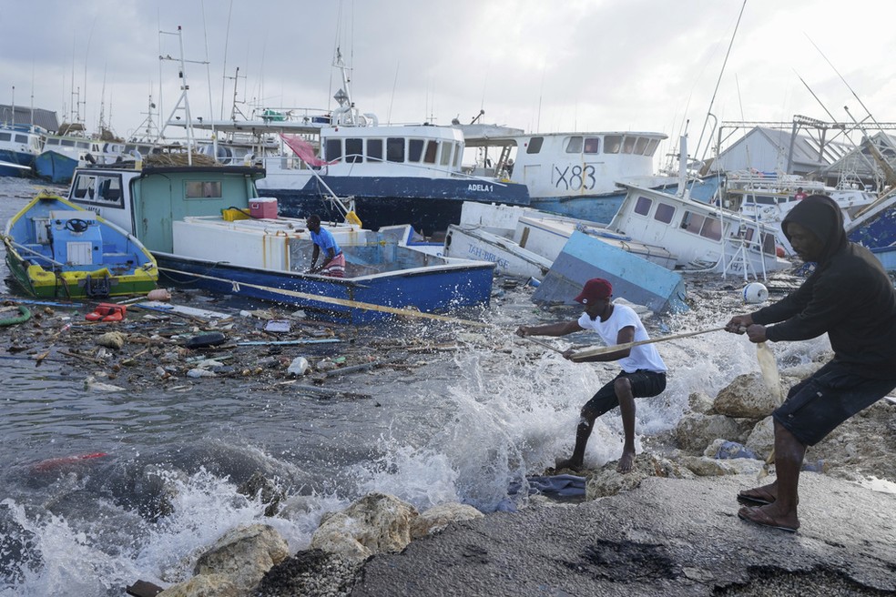 Homens puxam barco atingido por passagem de furacão Beryl em Bridgetown, em Barbados, em 1º de julho de 2024. — Foto: Ricardo Mazalán/ AP