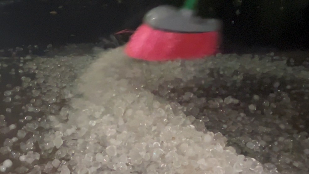 Moradores recolheram o granizo usando vassouras. — Foto: Wagner Alexandre