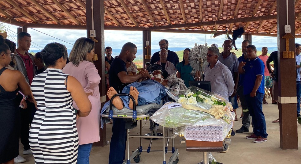 Deitada em maca, sobrevivente acompanha velório de filha em acidente com 25 mortos na Bahia — Foto: Filipe Costa
