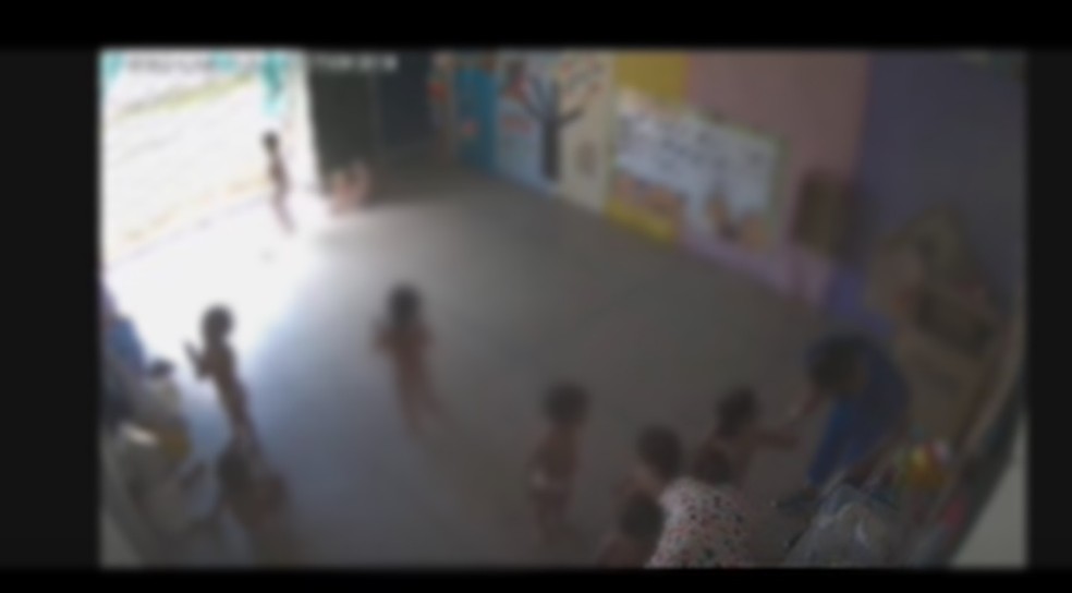 Funcionária abaixada fazendo foto de criança de costas — Foto: Reprodução/TV Cabo Branco