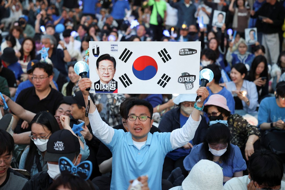 Homem em Seul exibe um cartaz com o rosto do candidato de centro-esquerda Lee Jae-myung, em 3 de junho de 2025. — Foto: Kim Hong-Ji/ Reuters