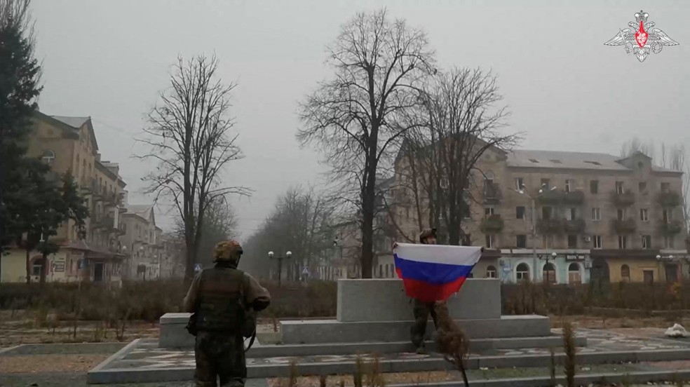 Soldado russo segura bandeira da Rússia em praça em Pokrovsk, cidade-chave da Ucrânia, em vídeo publicado em 1º de dezembro de 2025. — Foto: Ministério da Defesa russo via Reuters