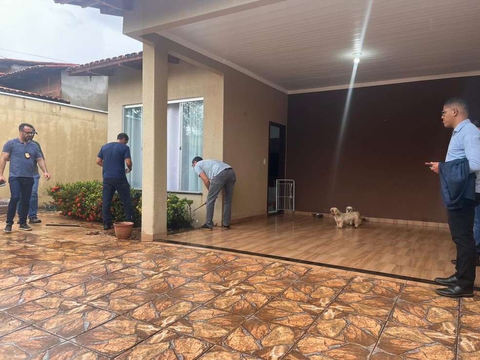 Agentes da polícia fazendo vistoria em casa onde dinheiro foi encontrado — Foto: Ana Paula Rebain