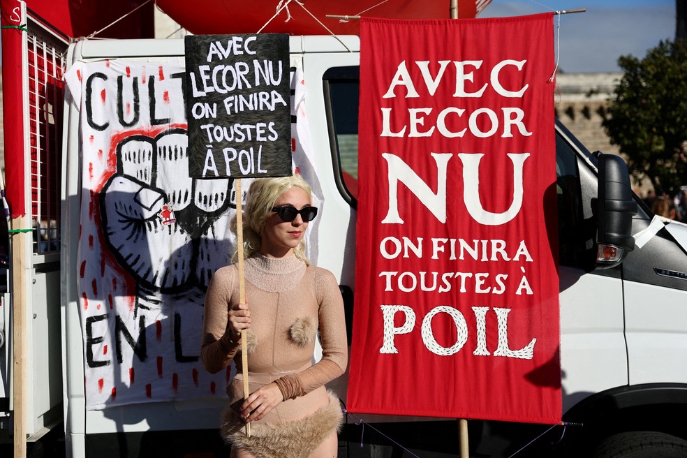 Um manifestante segura um cartaz com os dizeres "Com Lecornu, todos nós vamos acabar pelados" durante uma manifestação em Nantes, como parte de um dia de greves e protestos nacionais contra o governo e os cortes previstos no próximo orçamento, com o apoio do movimento "Bloquons Tout" (Vamos Bloquear Tudo) — Foto: REUTERS/Stephane Mahe