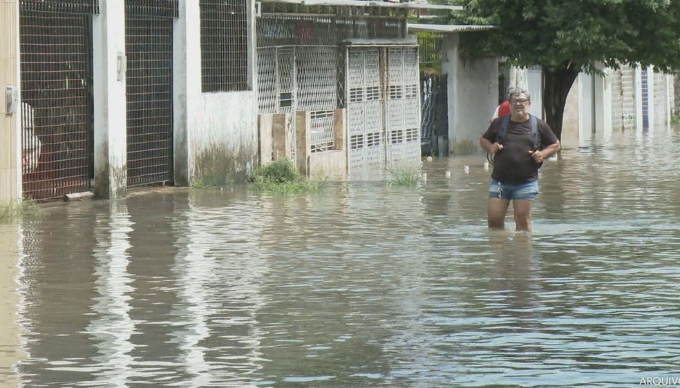 Pedestre anda em rua alagada no Recife — Foto: Reprodução/TV Globo