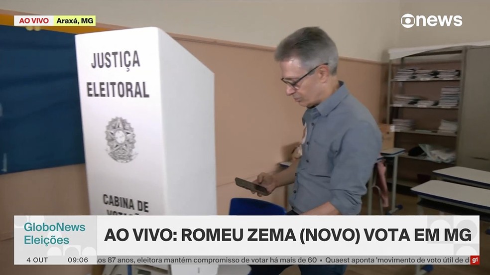 Momento em que o candidato à presidência da República, Romeu Zema, vai para cabine de votação com celular nas mãos. — Foto: GloboNews