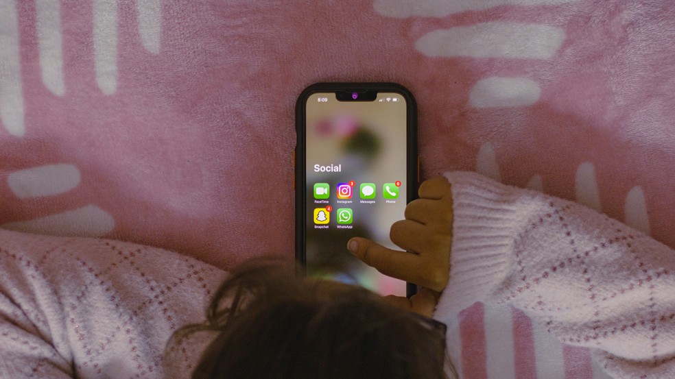 Criança mexendo no celular com as redes sociais visíveis no aparelho. — Foto: Unsplash/Sanket Mishra
