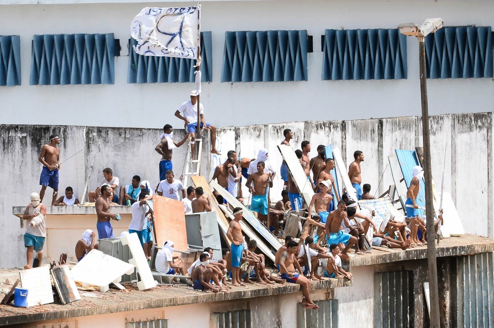Presidiários se reúnem no telhado durante rebelião no Centro Penitenciário de Alcaçuz, perto de Natal (RN), para evitar confronto com facções. No  fim de semana, 26 detentos do presídio morreram em uma rebelião que durou mais de 14 horas — Foto: Andressa Anholete/AFP