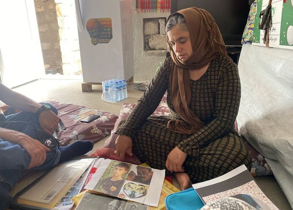Bahar olha as fotos de seu marido e filho mais velho, supostamente mortos pelo Estado Islâmico — Foto: BBC