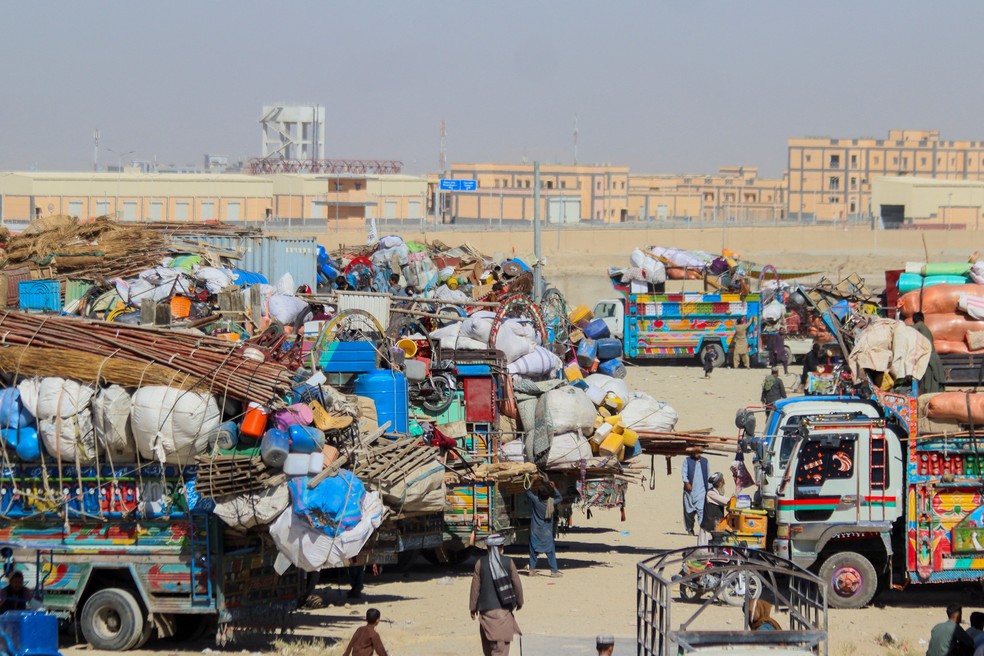 Pessoas passam por veículos estacionados com pertences de cidadãos afegãos, enquanto retornam ao seu país, depois do Paquistão fechar a fronteira. — Foto: Saeed Ali Achakzai/Reuters