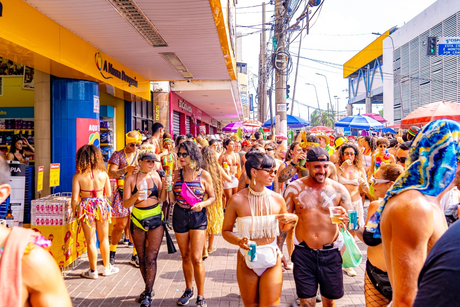 Afro-Brasileiros de favela enfrentam calor em bloco de Caxias sob sol.