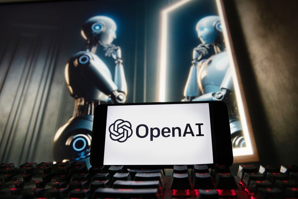 Logotipo da OpenAI em um celular diante de uma imagem gerada pelo DALL·E, ferramenta de criação de imagens do ChatGPT. — Foto: Michael Dwyer/AP