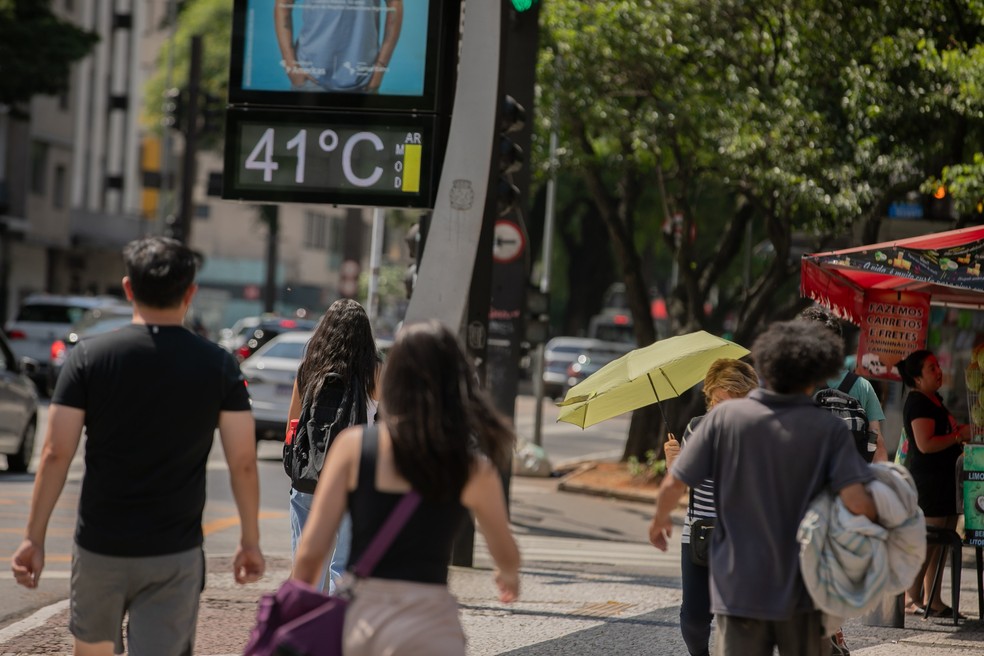 Pessoas caminham e se protegem do sol e calor em via com termômetro marcando 41°C em São Paulo, em 13 de novembro de 2023 — Foto: BRUNO ROCHA/ENQUADRAR/ESTADÃO CONTEÚDO