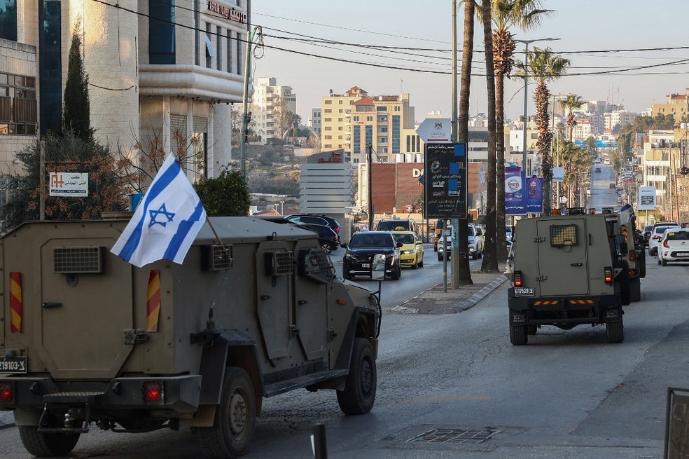 Veículos militares israelenses cruzam avenida em Ramallah, capital da Cisjordânia — Foto: Zain Jaafar/AFP