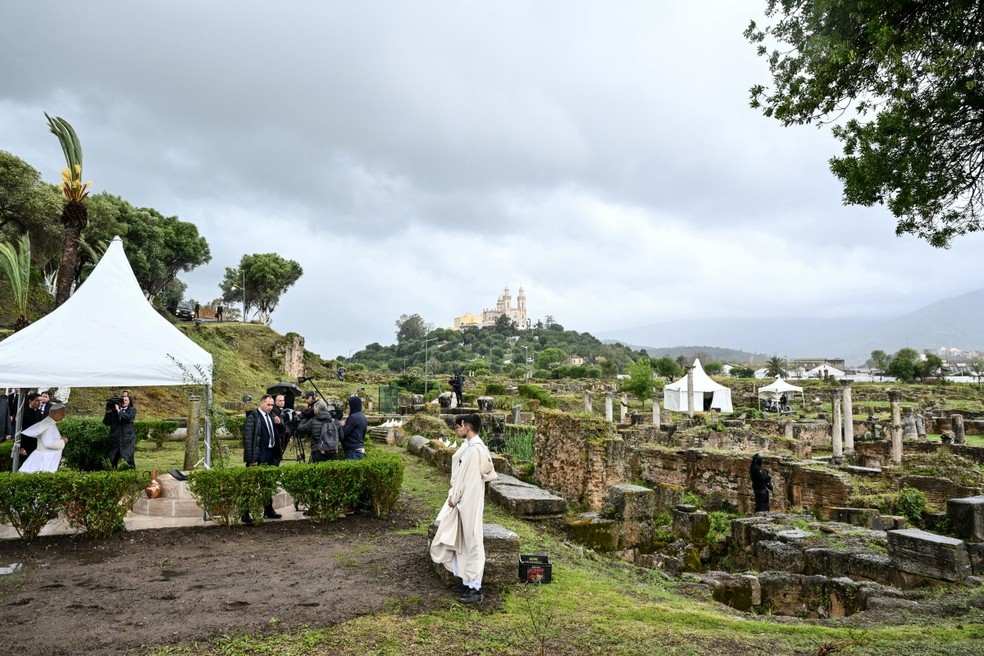 Papa Leão XIV (à esquerda) reza durante uma visita ao sítio arqueológico de Hipona, em Annaba — Foto: AFP