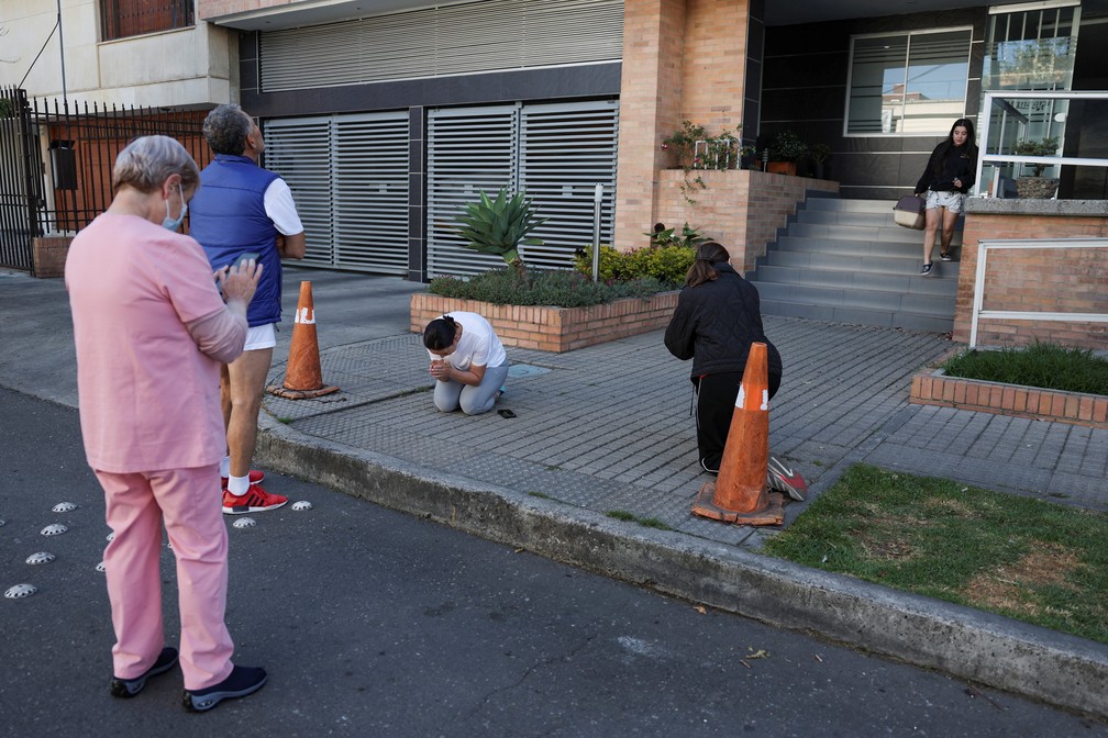 Uma mulher reza enquanto pessoas se reúnem do lado de fora de um prédio após um terremoto em Bogotá, capital da Colômbia, em 10 de agosto de 2026. — Foto: Luisa Gonzalez/Reuters