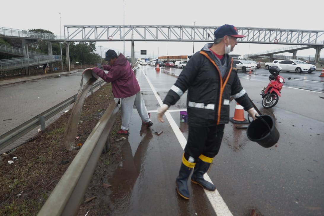 Moradores de bairro alagado tiram água de balde e jogam em rodovia durante manifestação em Porto Alegre