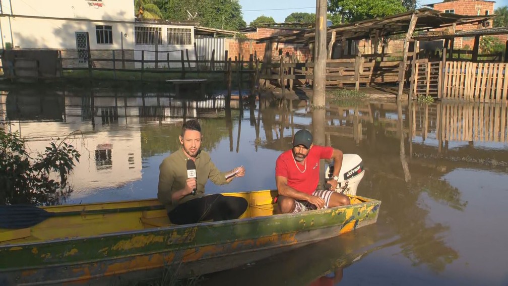 Morador usa barca para ajudar vizinhos ainda ilhados em Seropédica — Foto: Reprodução/TV Globo
