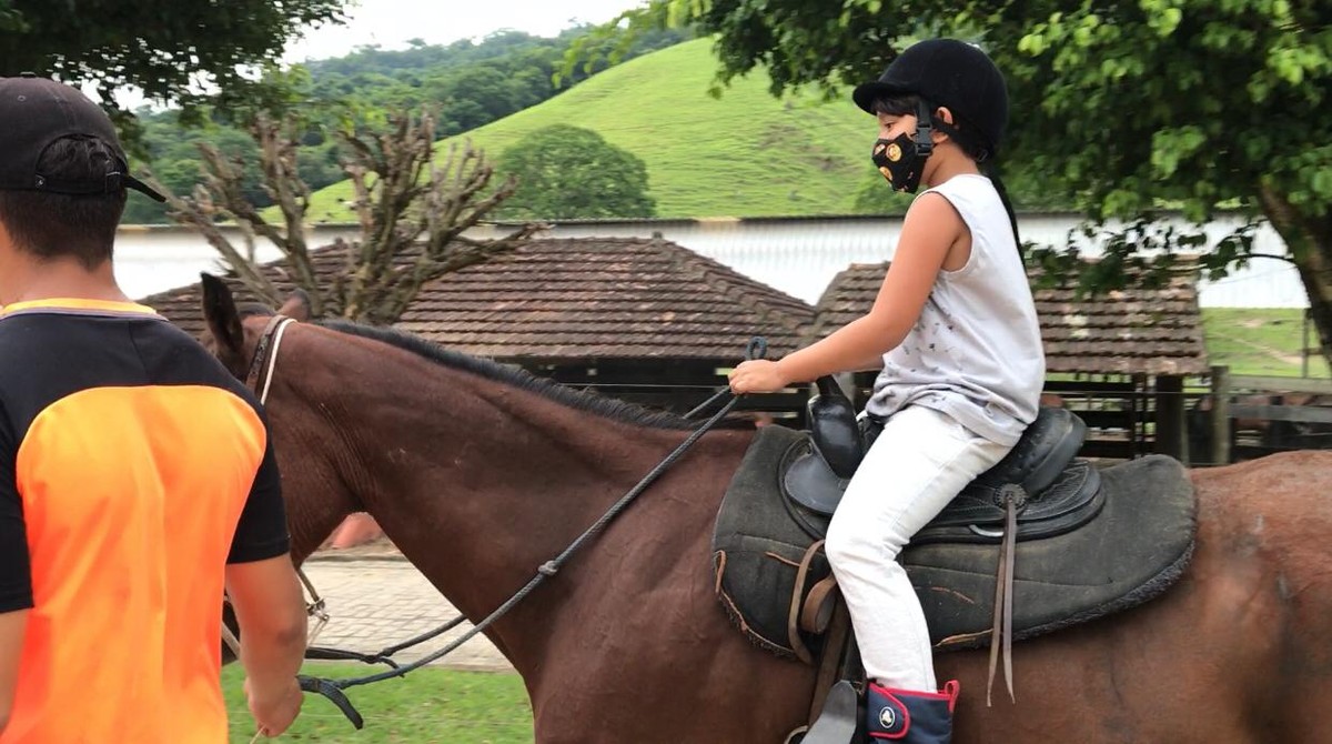 Jovem cavaleiro montando um cavalo pulando uma cerca em uma