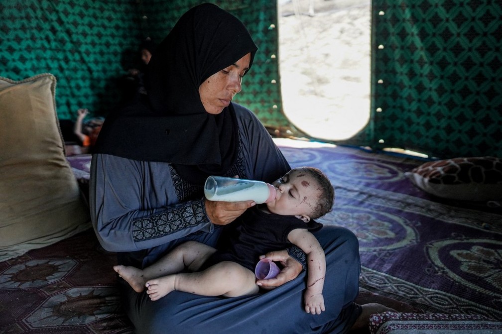 Bebê é alimentado após ser o único sobrevivente de bombardeio que matou sua família — Foto: Bashar TALEB / AFP