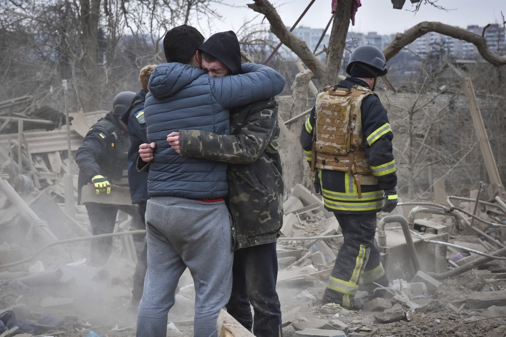 Homens se abraçam após um ataque da Rússia na cidade de Zaporizhzhia, na Ucrânia, em 22 de março de 2023. — Foto: Andriy Andriyenko/ AP