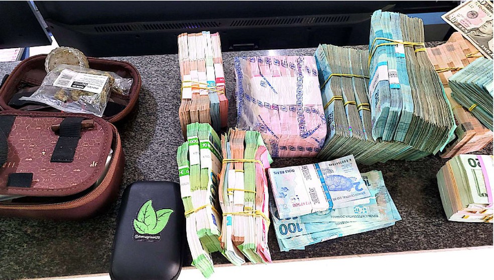 Parte do dinheiro encontrado com o casal, nécessaire com skunk no lado esquerdo da imagem. — Foto: Reprodução
