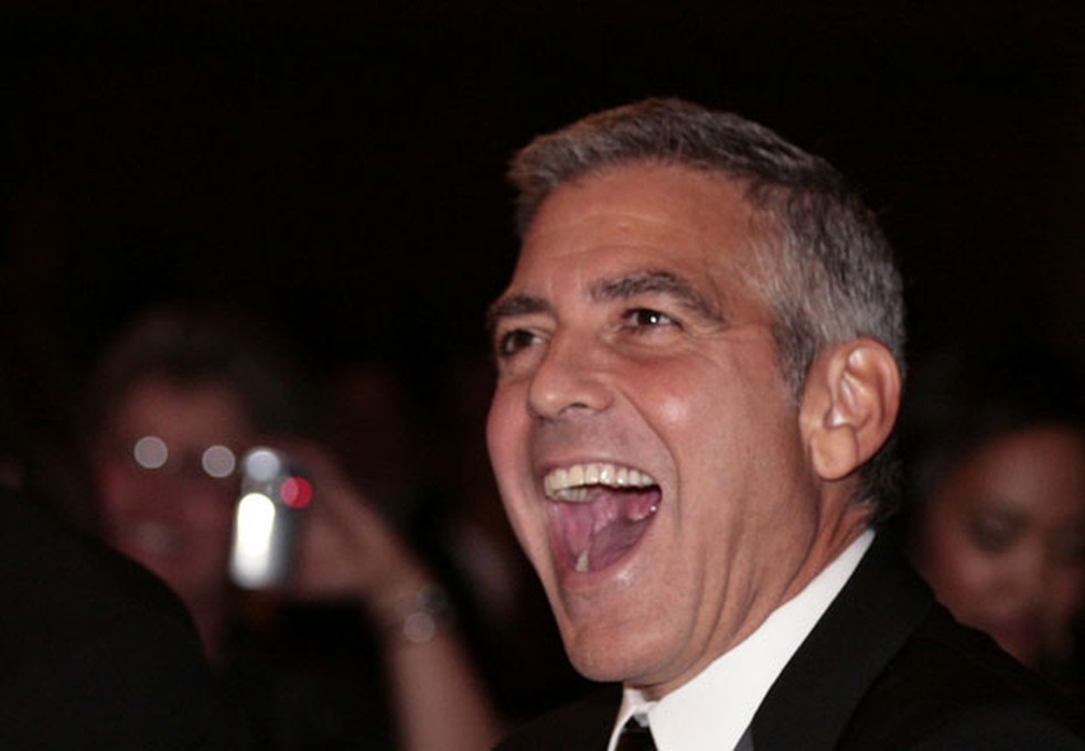 O ator George Clooney ri durante evento na Casa Branca — Foto: AP 