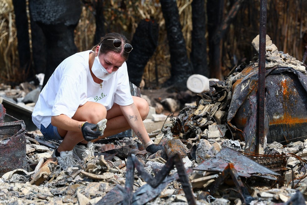 Mulher faz busca na casa dos pais depois do incêndio que devastou região da França. — Foto: Yves Herman/Reuters