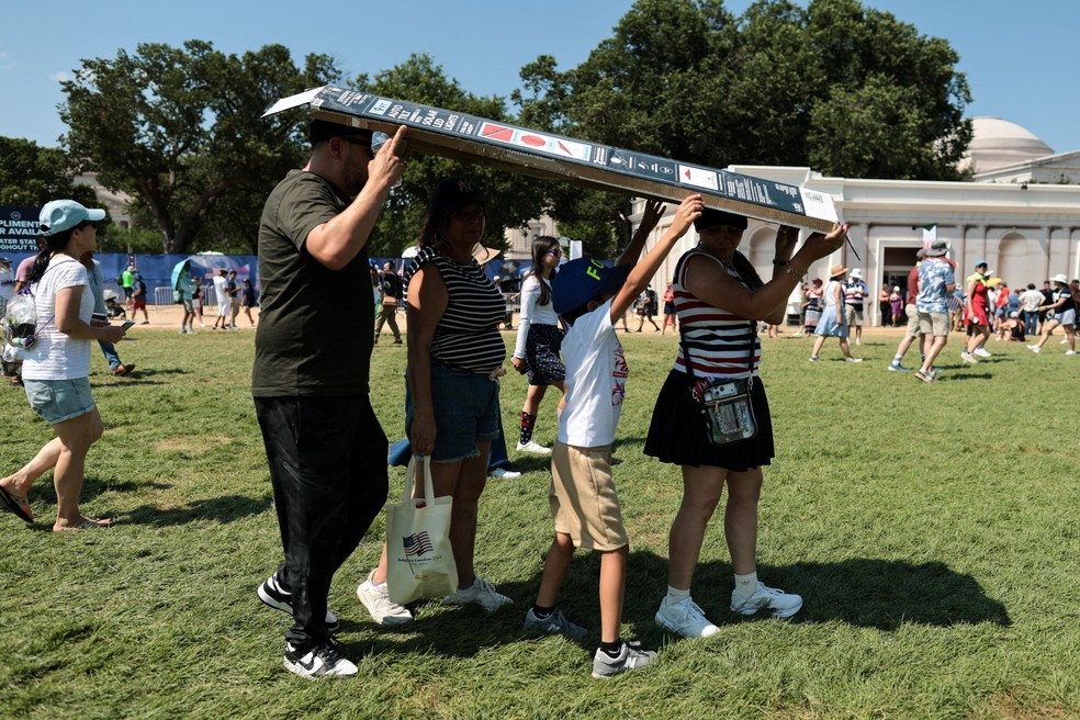 Família usa caixa de papelão para se proteger de sol na Great American State Fair, no National Mall, em Washington D.C., em 4 de julho de 2026. — Foto: REUTERS/Jonathan Ernst