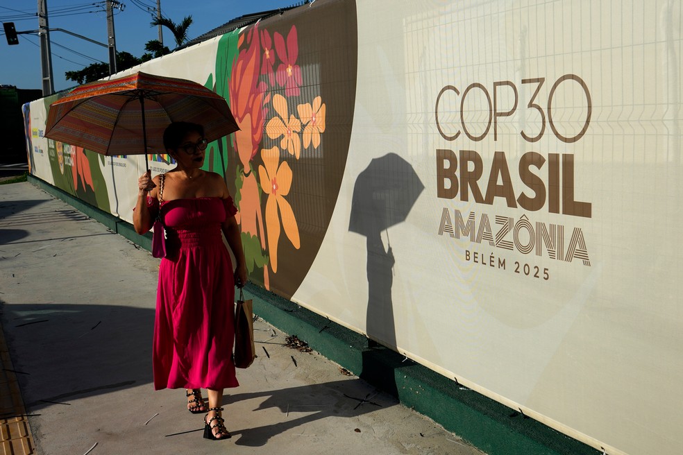 Mulher caminha em frente à logo da COP30. — Foto: AP Photo/Eraldo Peres