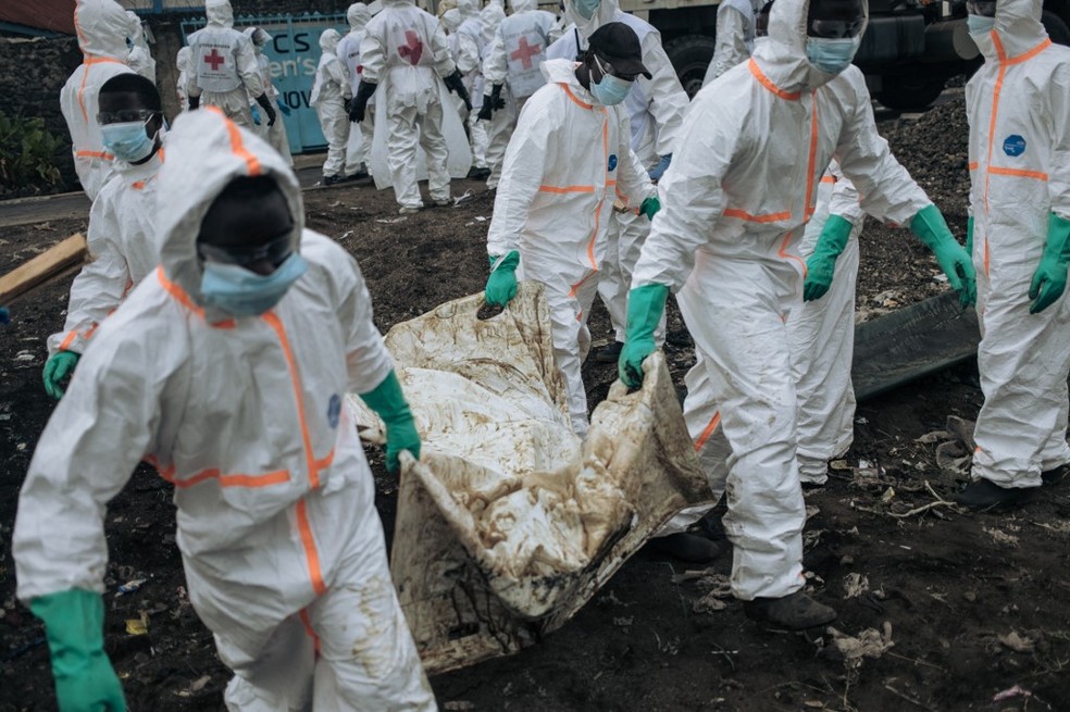 Membros da Cruz Vermelha enterrando vítimas de conflito no Congo — Foto: ALEXIS HUGUET / AFP