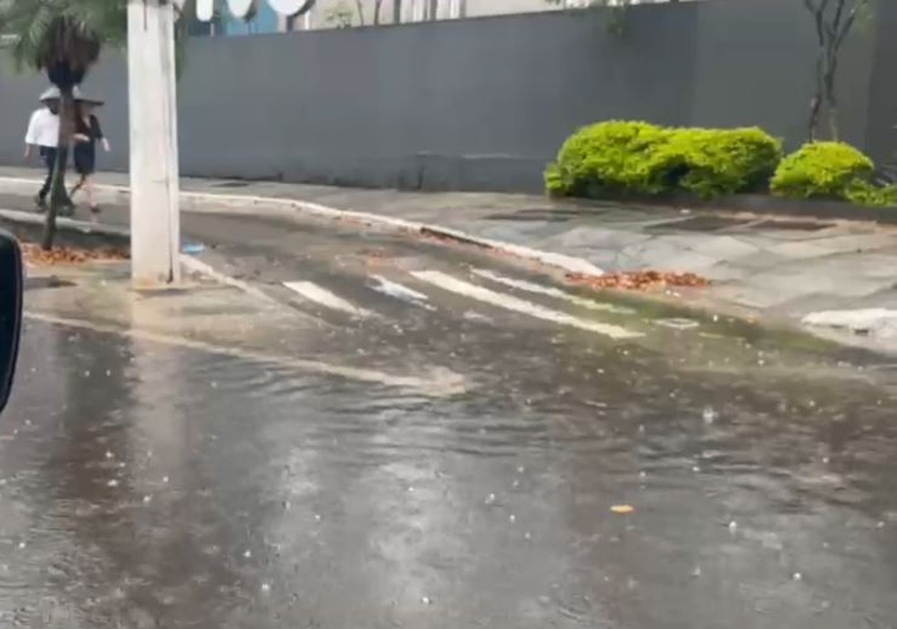 Casal se protege da chuva deste domingo (19) que alaga calçada e parte da rua no Brooklin, Zona Sul de São Paulo — Foto: Maurício Ferraz/TV Globo