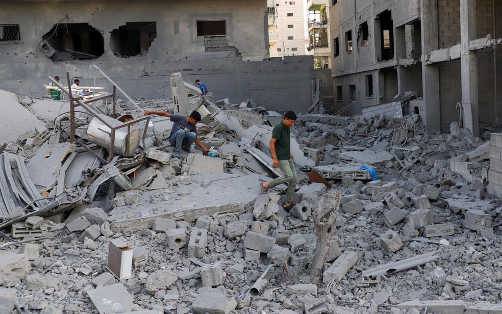Palestinos inspecionam os danos em um bairro residencial, após uma operação israelense na área, na Cidade de Gaza. — Foto: Ebrahim Hajjaj/Reuters