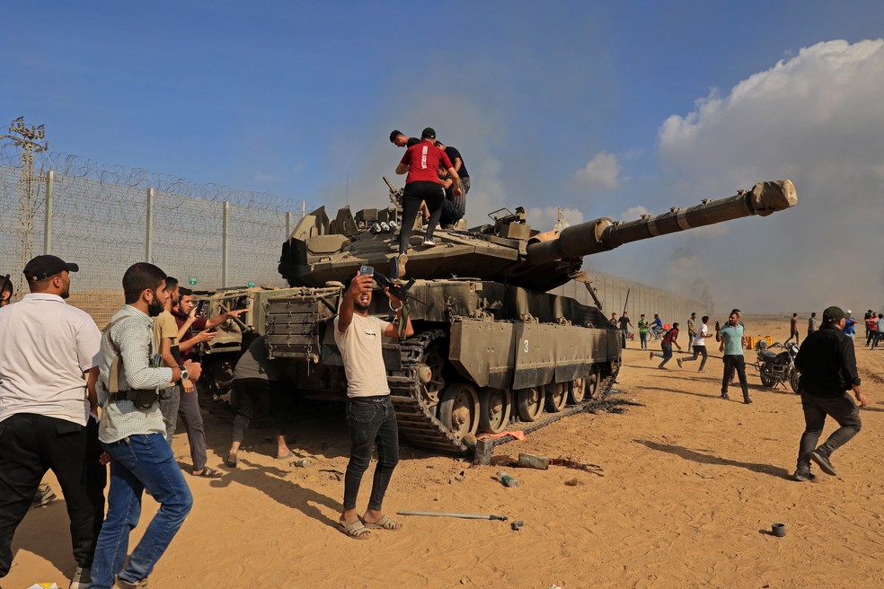Palestinos assumem o controle de tanque israelense depois de cruzar a fronteira de Israel com Khan Yunis, no sul da Faixa de Gaza, em 7 de outubro de 2023. — Foto: Said Khatib/AFP