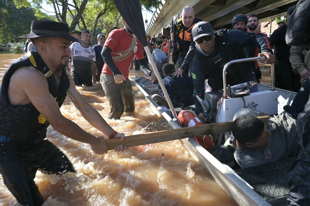 6 de maio - Homem usa um pedaço de madeira para agredir um suspeito de furtar casas em meio ao caos provocado pelo alagamento em Porto Alegre — Foto: Nelson Almeida/AFP