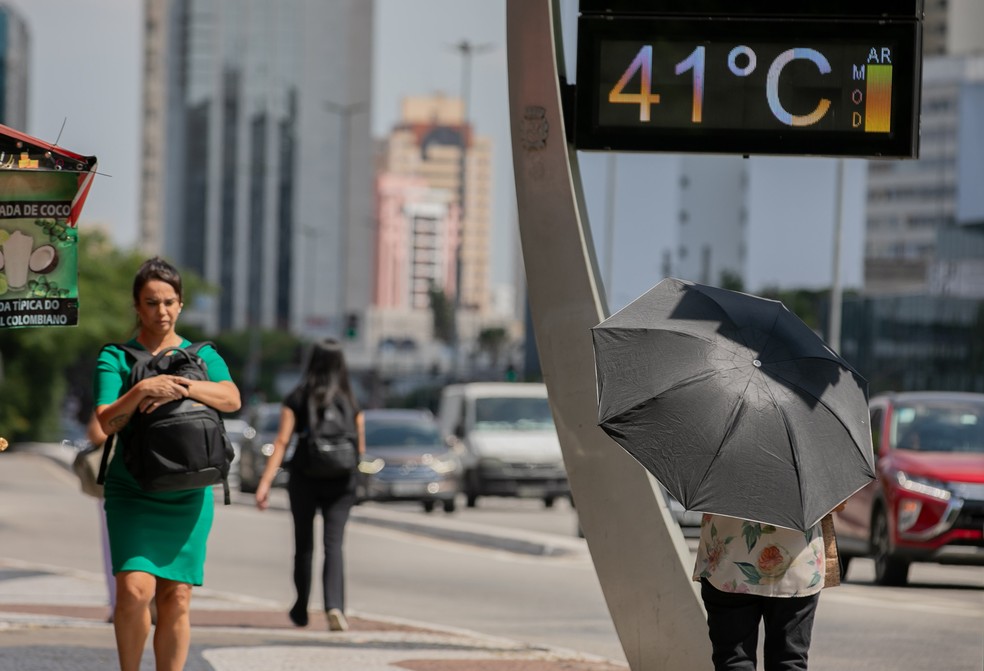 Pessoas caminham e se protegem do sol e calor em via com termômetro marcando 41°C graus da zona sul de São Paulo — Foto: BRUNO ROCHA/ENQUADRAR/ESTADÃO CONTEÚDO