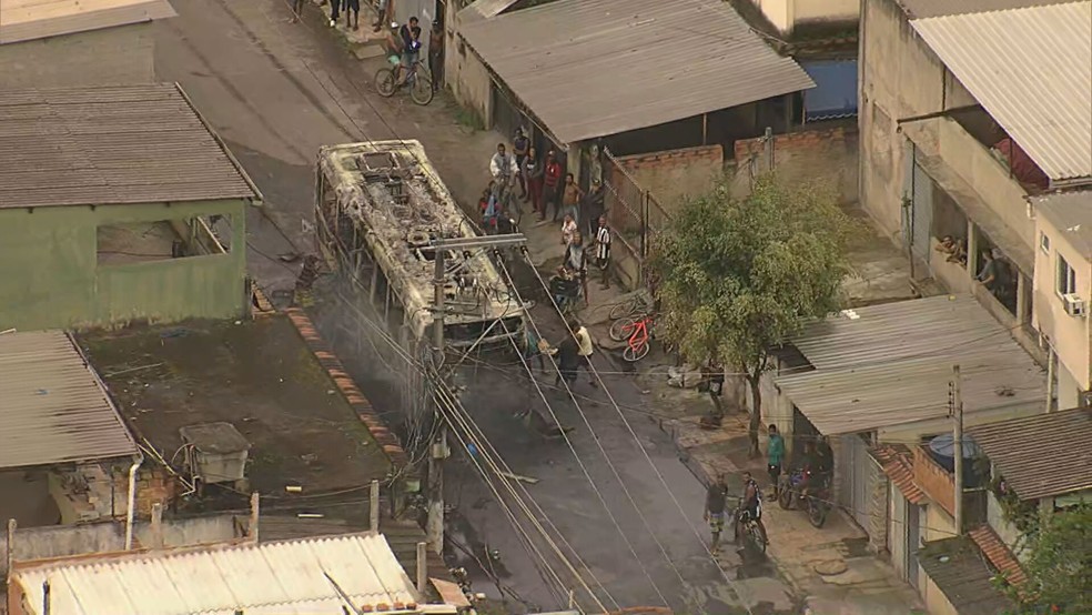 Moradores removem partes metálicas de carcaça de ônibus que foi incendiado — Foto: Reprodução/TV Globo