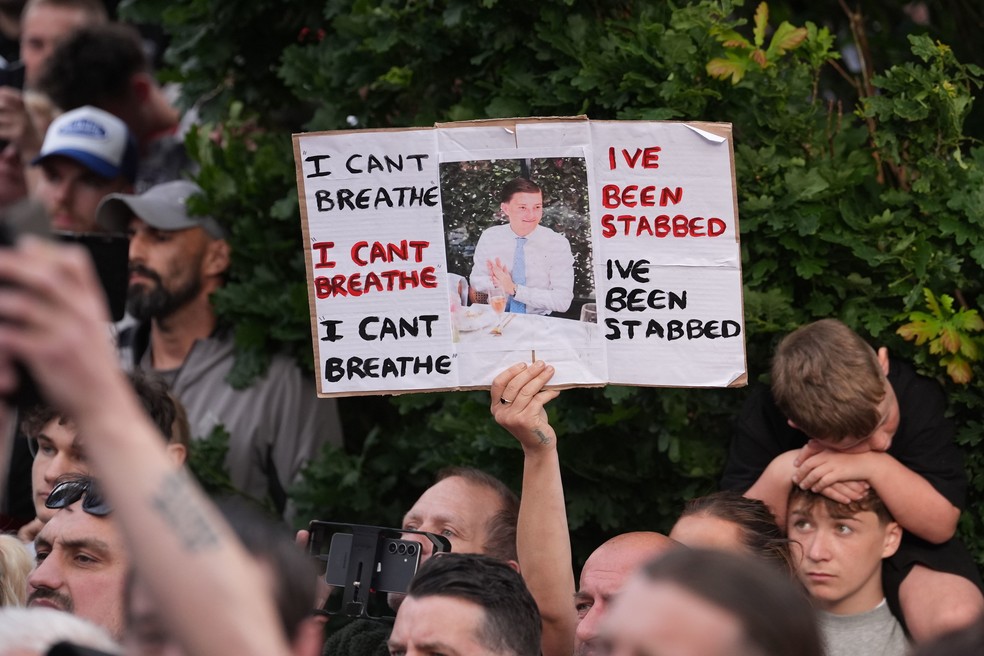 Cartaz mostra as frases 'não consigo respirar' e 'fui esfaqueado', ditas por Nowak enquanto a polícia o algemava. — Foto: Gareth Fuller/PA via AP