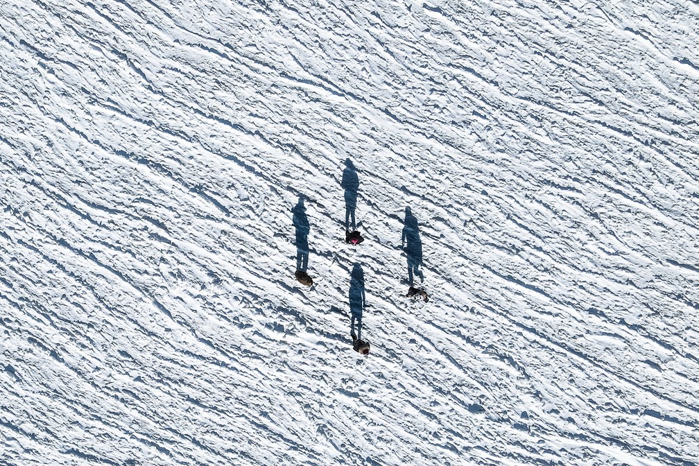 A fotografia 'Frozen Shadows, de Yevhen Samuchenko, mostra quatro pessoas andando sobre um mar congelado na Ucrânia. A região, ao norte do Mar Negro, congela regularmente poruque é alimentada por água doce dos rios Don, Danúbio e Dnieper, que congela a uma temperatura mais alta do que a da água salgada. — Foto: Yevhen Samuchenko