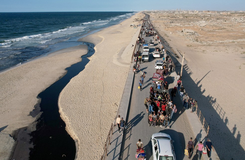 Palestinos que foram deslocados para a parte sul de Gaza seguindo por uma estrada para retornar ao norte após o cessar-fogo, em 10 de outubro de 2025 — Foto: REUTERS/Stringer