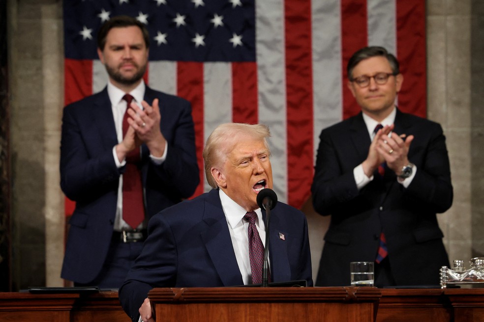 O presidente Donald Trump discursa em uma sessão conjunta do Congresso no Capitólio dos EUA em 4 de março de 2025, em Washington, DC. O vice-presidente JD Vance e o presidente da Câmara, Mike Johnson (R-LA), aplaudem atrás dele. — Foto: Win McNamee/Pool via REUTERS