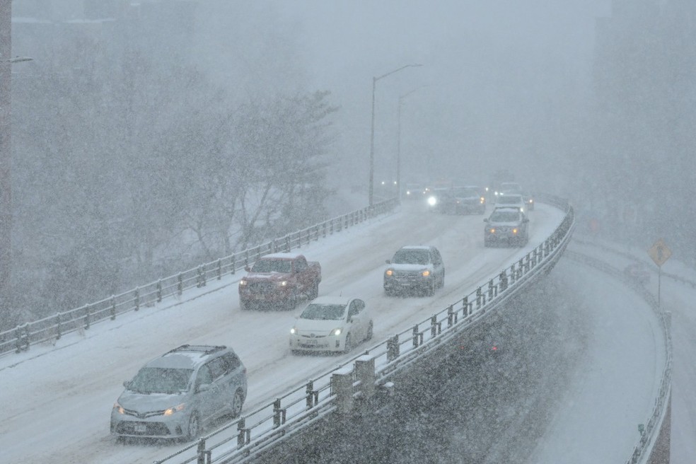 Veículos trafegam em uma estrada coberta de neve no bairro do Brooklyn, na cidade de Nova York. — Foto: ANGELA WEISS / AFP