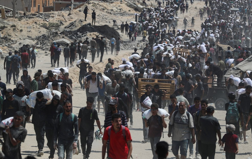 Palestinos carregam suprimentos de ajuda humanitária em Gaza neste domingo (27) — Foto: Mahmoud Issa/Reuters